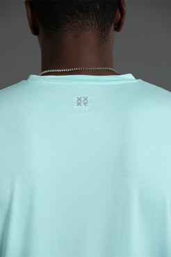 Light blue t-shirt with a logo on the back, worn by a person against a gray background || Aqua Heather
