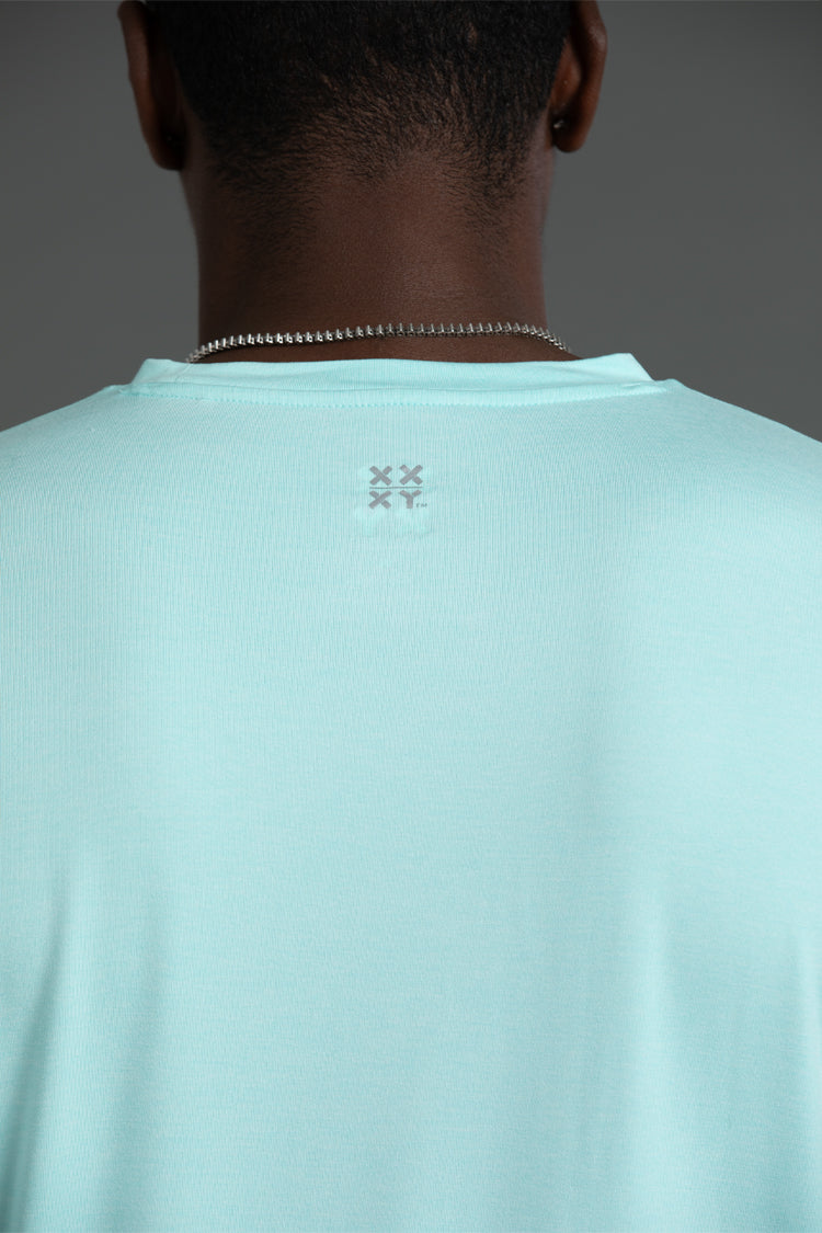 Light blue t-shirt with a logo on the back, worn by a person against a gray background || Aqua Heather