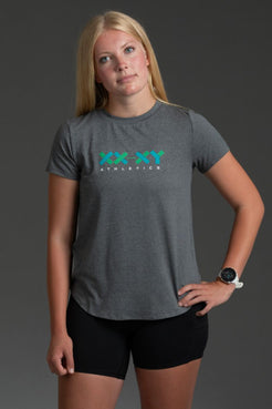 Woman wearing a gray t-shirt with a logo and black shorts on a dark background || Black/Dark Heather Gray/White