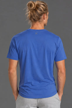 Back view of male model wearing the blue XX-XY Athletics Logo Tee with light gray athletic shorts. || Cobalt Blue