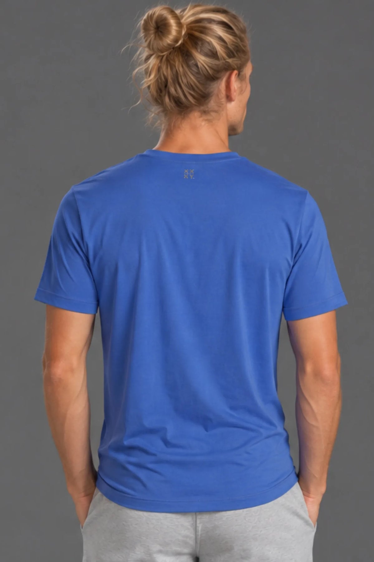 Back view of male model wearing the blue XX-XY Athletics Logo Tee with light gray athletic shorts. || Cobalt Blue