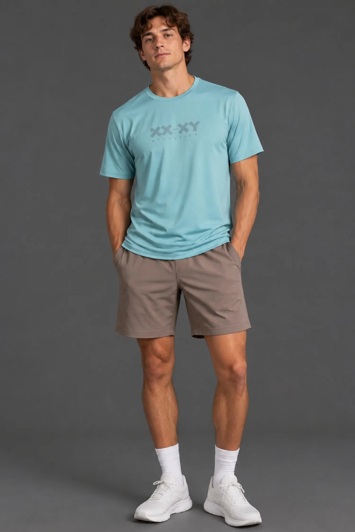 Male model wearing the Men’s XX-XY Athletics Logo Tee in light blue with mocha athletic shorts.