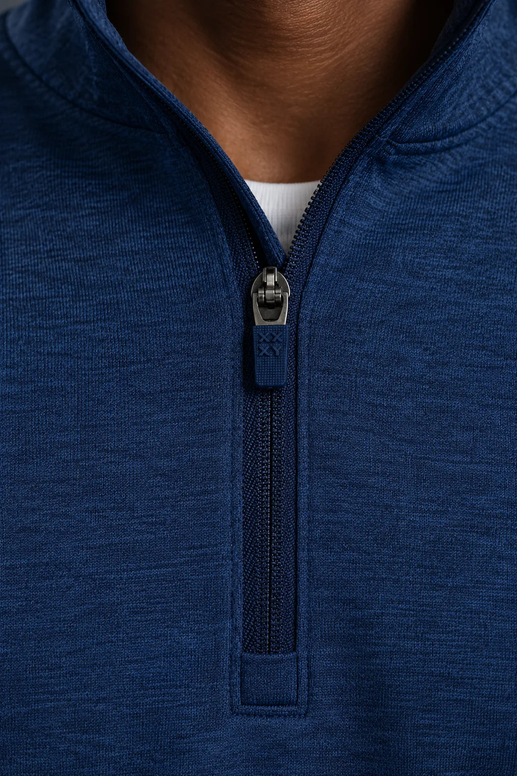 Close-up of a man wearing a navy blue heathered quarter-zip pullover with a stand collar, showing the zipper and a small white undershirt at the neckline. || Navy