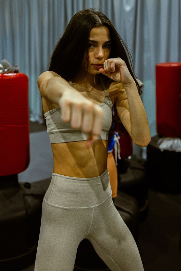Woman in athletic wear posing with fists up in a gym setting