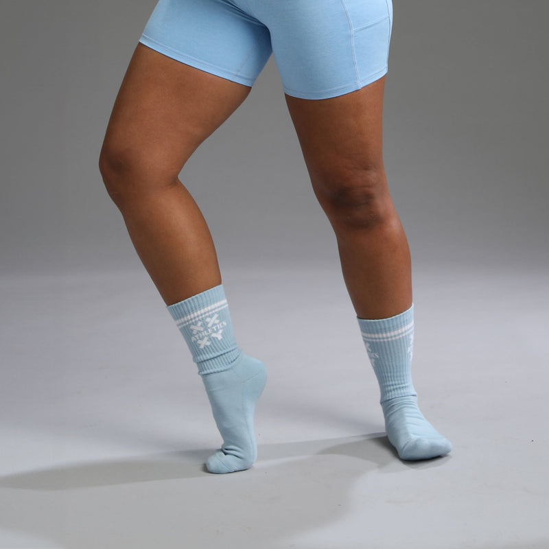 A pair of light blue, half-calf socks with a pattern, worn on a person's legs. || light blue
