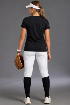 Rear view of a female softball player wearing a black XX-XY Athletics T-shirt with a blank back, white softball pants, black knee-high socks, and a white visor while holding a brown softball glove. || Black