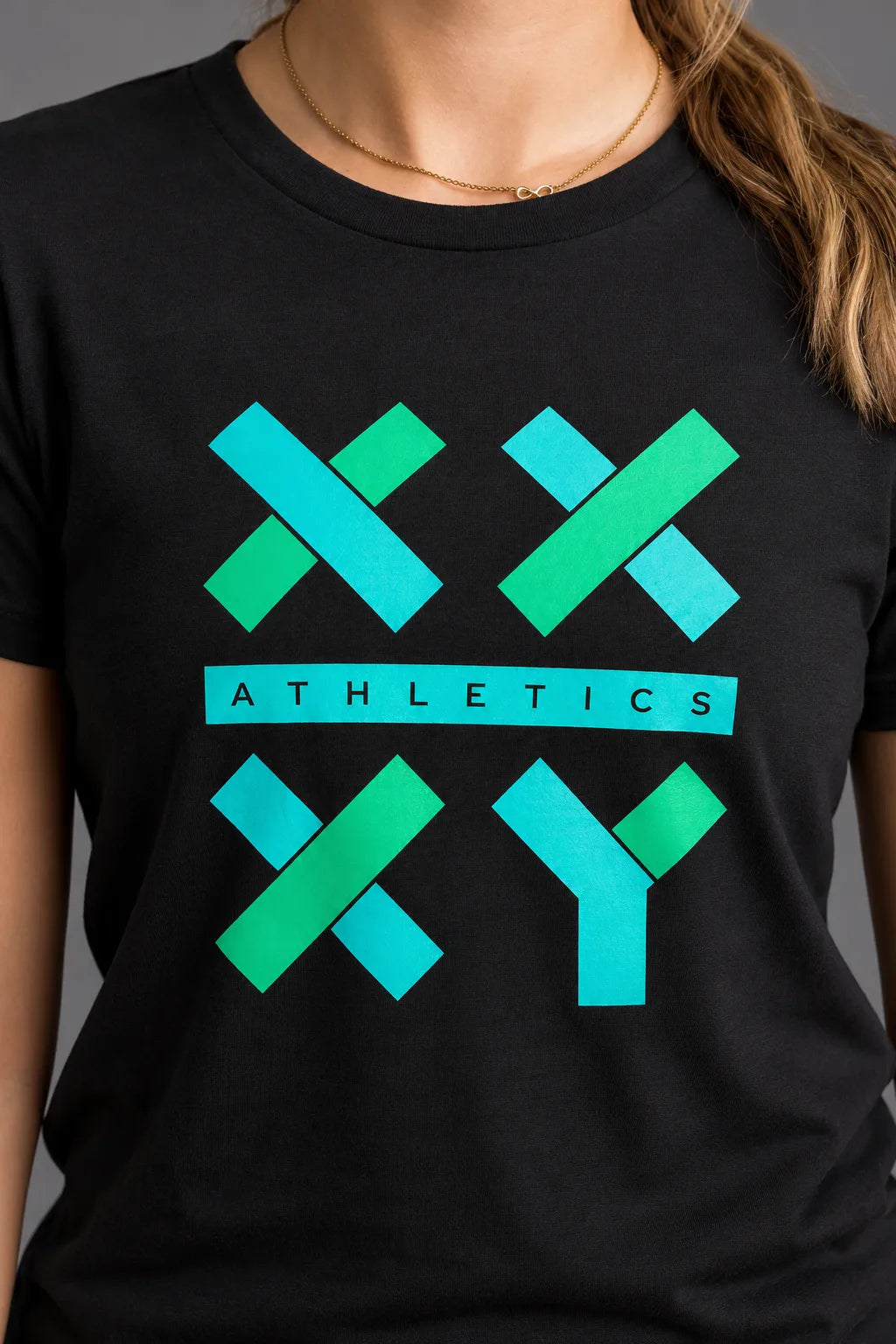 Close-up of a black women's XX-XY Athletics T-shirt featuring a turquoise and green graphic logo across the chest.