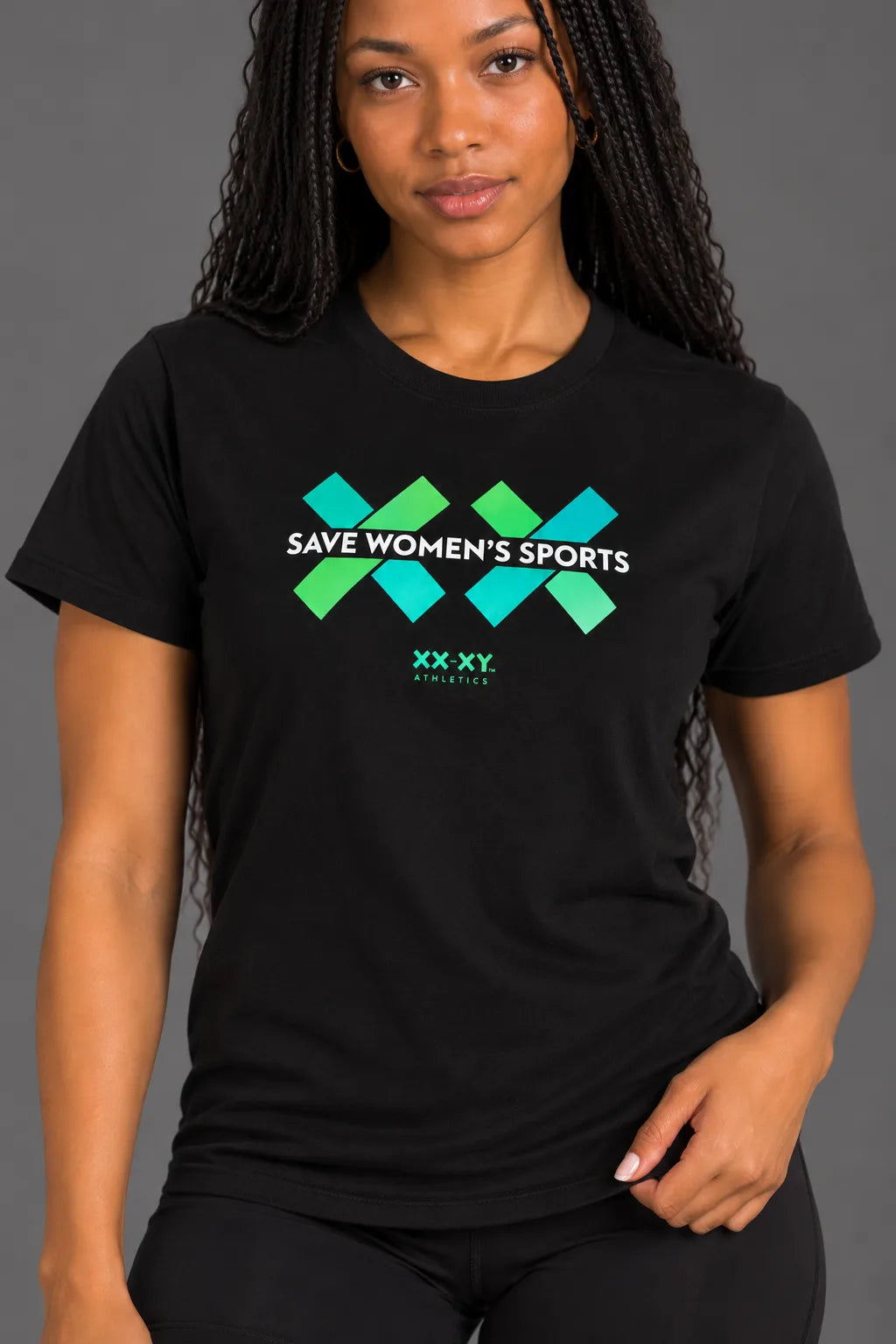 Female model smiling while wearing a black Save Women's Sports graphic tee with her hand resting on the shirt hem || Black
