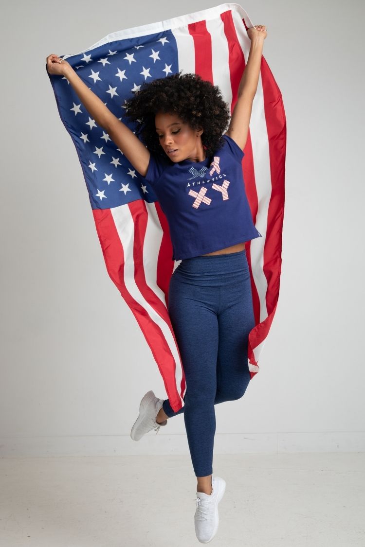 Person holding an American flag wearing a blue outfit with a graphic design. || navy