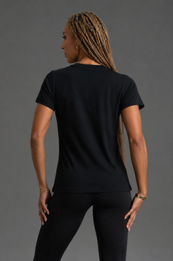 Woman wearing a black t-shirt facing backwards on a gray background || Black