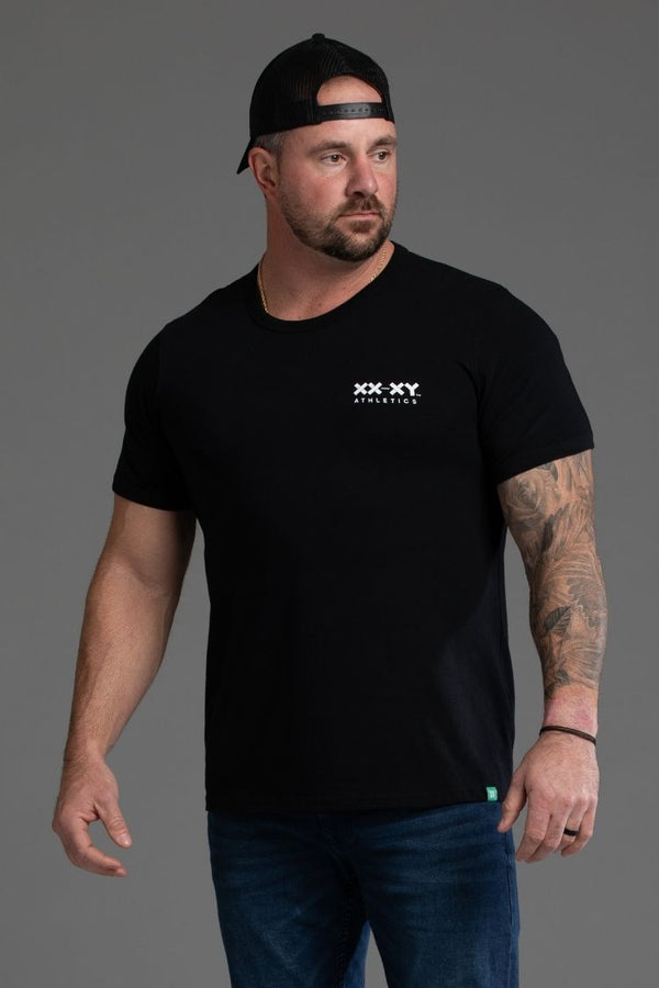 Man wearing a black t-shirt with a logo on a gray background || black