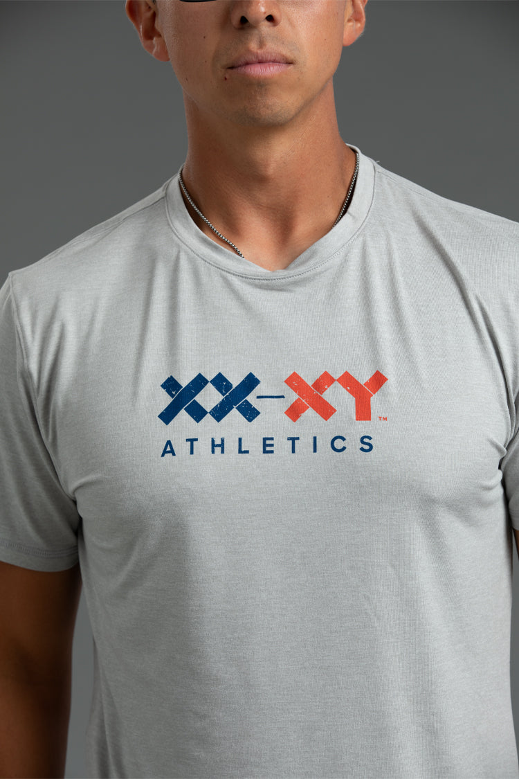 Person wearing a gray t-shirt with XX-XY Athletics logo || Light Heather Gray - 1