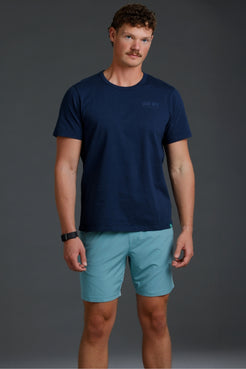 Man wearing a navy t-shirt and light blue shorts on a gray background || Underseas