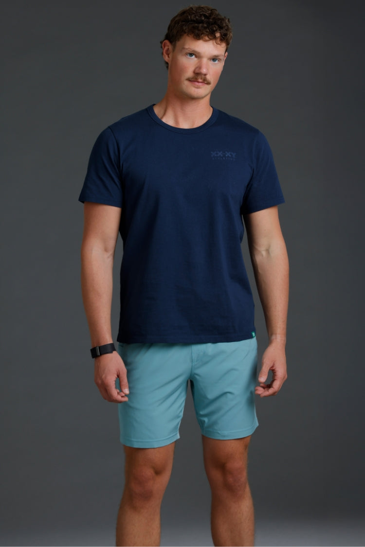 Man wearing a navy t-shirt and light blue shorts on a gray background || Underseas