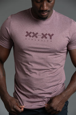 Person wearing a maroon t-shirt with 'XXXY Athletics' logo on a gray background || Burgundy Heather