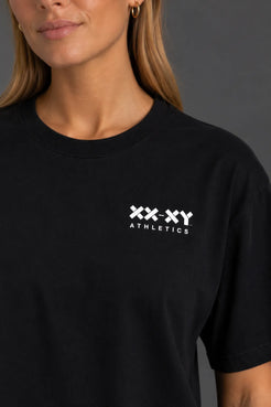 Close-up of the white XX-XY Athletics chest logo on a black boyfriend-fit tee. || Black