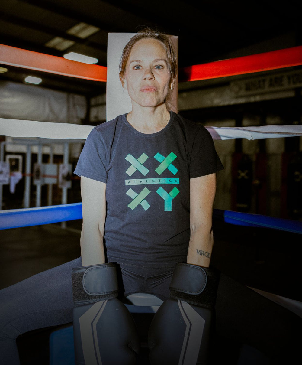 Person wearing a dark t-shirt with a logo in a boxing ring