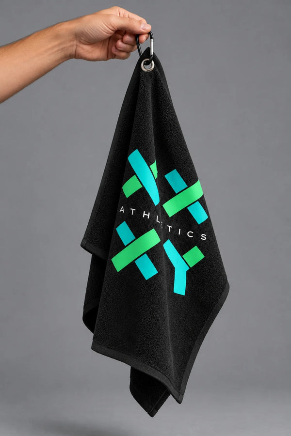 Hand holding a black XX-XY Athletics golf towel by its carabiner, showcasing the turquoise and green logo against a gray background || Black