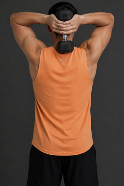 Person wearing an orange tank top lifting a dumbbell with a dark background || Light Orange