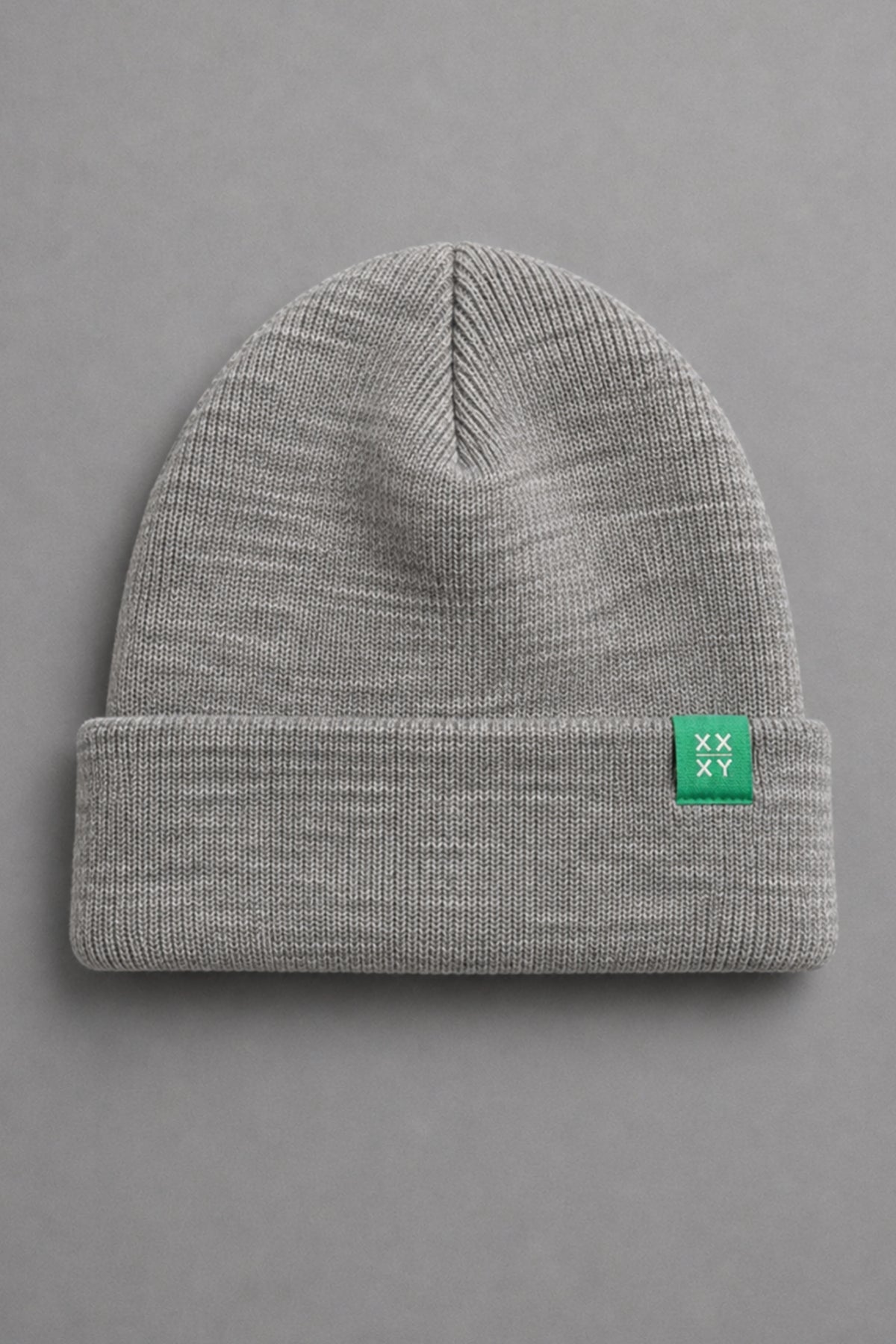 A light gray heathered knit beanie with a folded cuff, featuring a small green square patch on the side with a white logo, set against a solid gray background. || Light Heather Gray