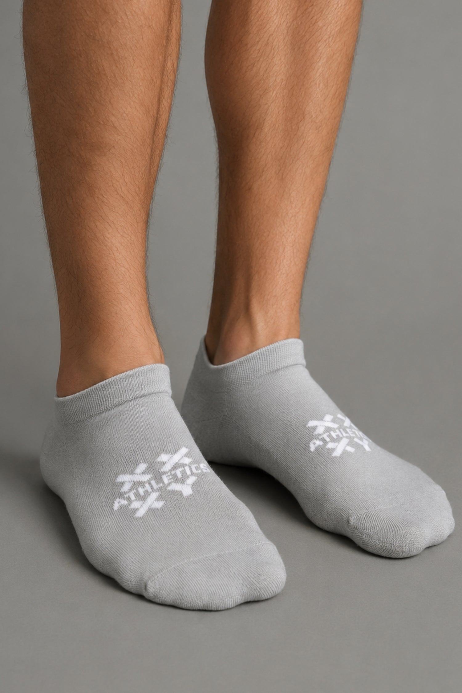 Gray socks with white logo worn by a person on a gray background