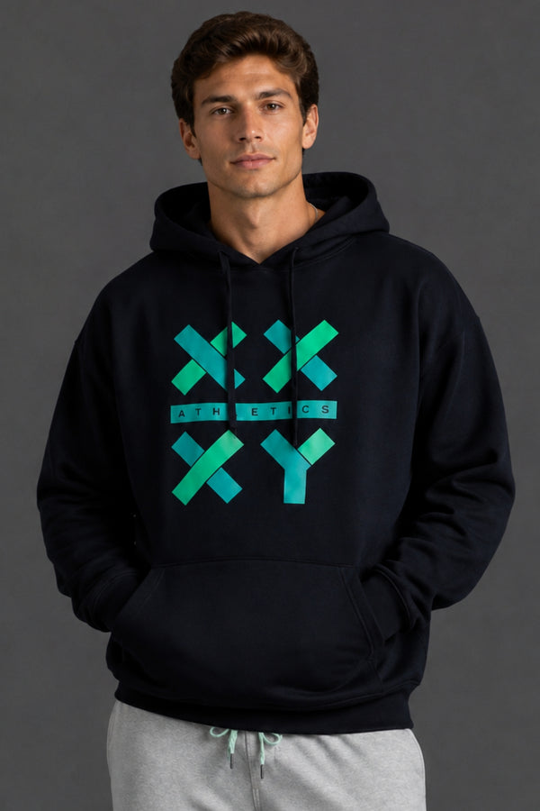 A man wearing a black pullover hoodie with a teal and green geometric 'XX ATHLETICS XY' graphic on the chest, paired with light gray sweatpants, against a dark gray studio background. || Black with Color Logo