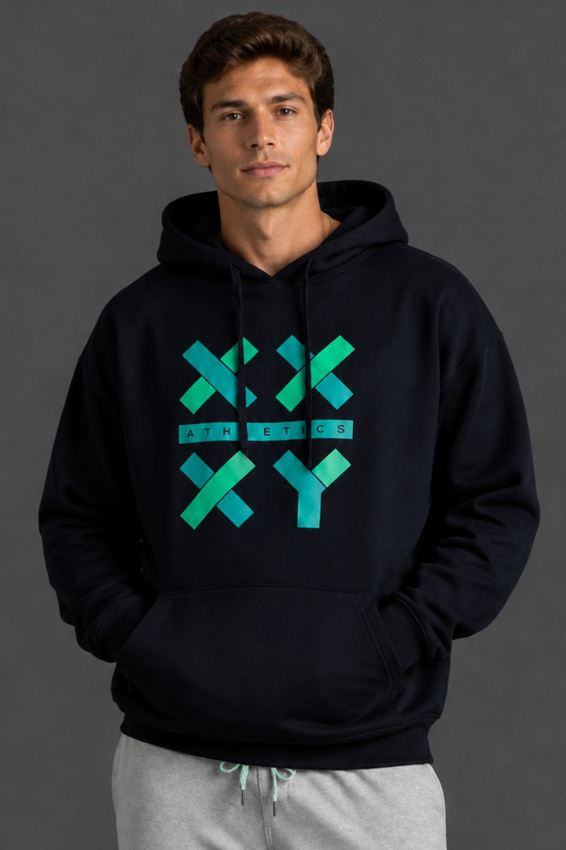 A man wearing a black pullover hoodie with a teal and green geometric 'XX ATHLETICS XY' graphic on the chest, paired with light gray sweatpants, against a dark gray studio background. || Black with Color Logo