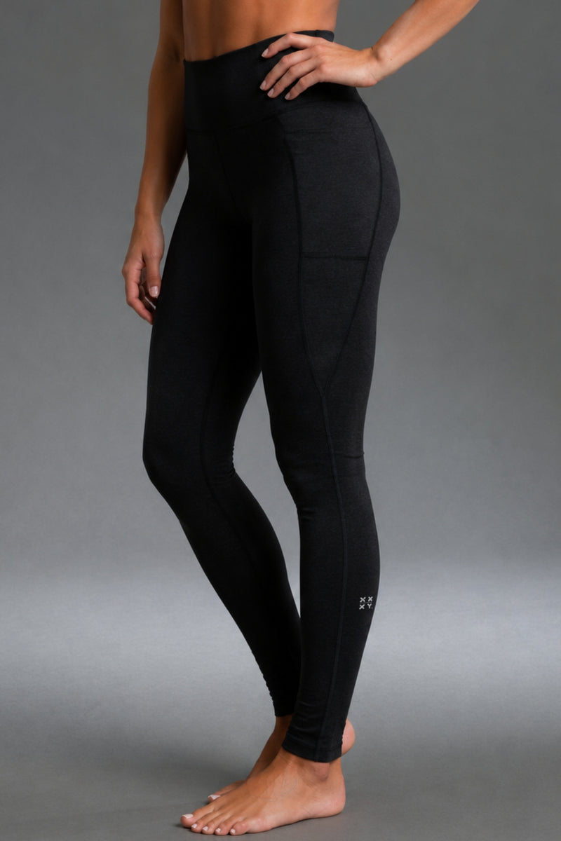 A model wearing black high-waisted athletic leggings with a side pocket, shown from the waist down against a neutral gray studio background. || Black Heather