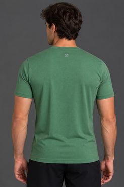 A man viewed from the back wearing a short-sleeve crew-neck t-shirt in a heathered green color, paired with black pants, against a solid dark gray studio background. || Hunter Green Heather