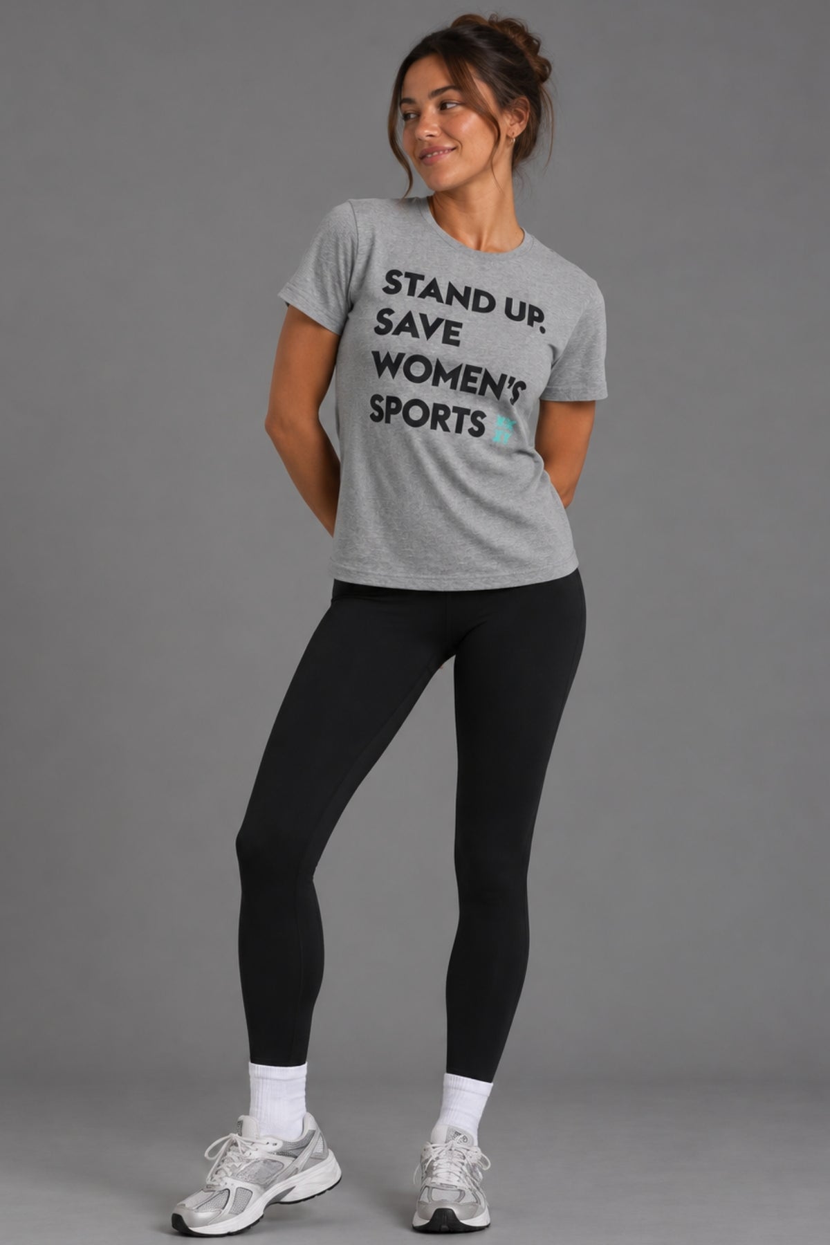 Woman wearing the gray Stand Up Save Women’s Sports tee with black leggings and sneakers