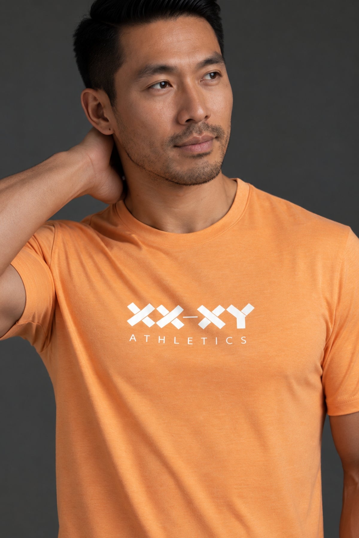 Male model wearing the XX-XY Athletics orange logo tee against a dark gray background. || Light Orange