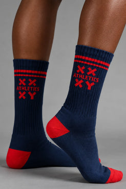 Navy socks with red accents worn by a person on a gray background || blue aster/red