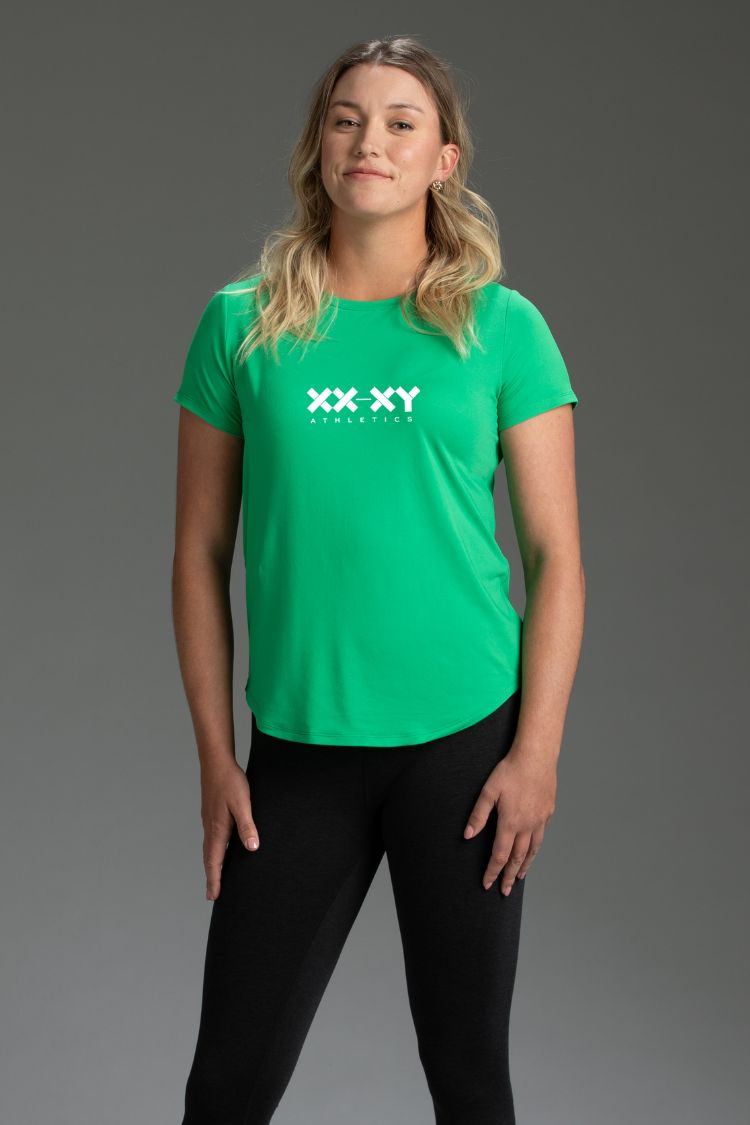 Person wearing a green t-shirt with a logo on a gray background || Kelly Green