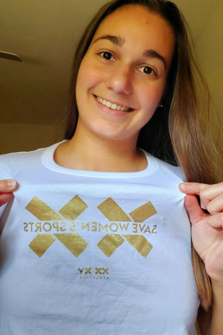 Person wearing a white t-shirt with gold text and logos