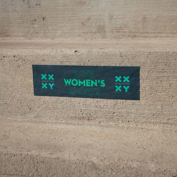 A bumper sticker with the text 'Save Women's Sports' displayed on a concrete surface.
