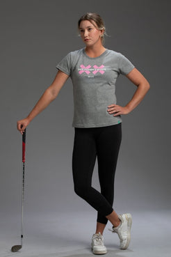 Woman wearing a gray t-shirt with a pink logo and text, holding a golf club on a gray background || Heather Gray