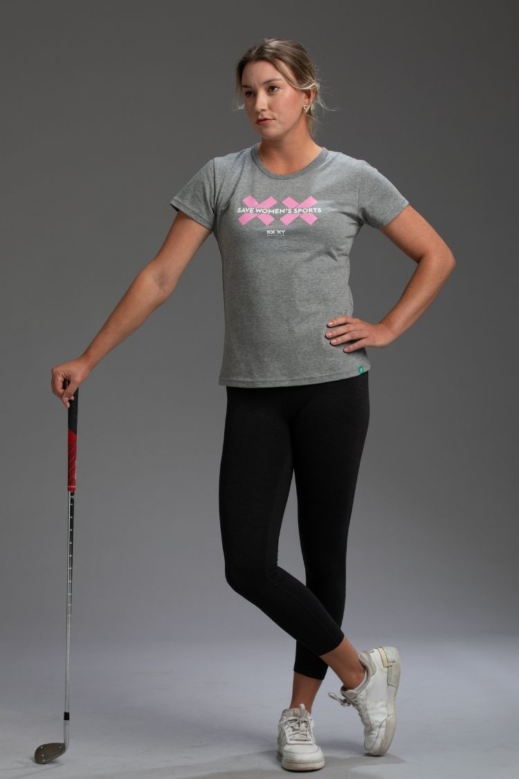 Woman wearing a gray t-shirt with a pink logo and text, holding a golf club on a gray background || Heather Gray