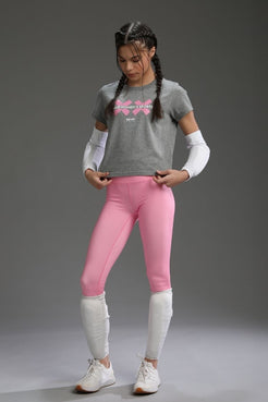 Person wearing a gray t-shirt with text and pink leggings on a gray background || Heather Gray