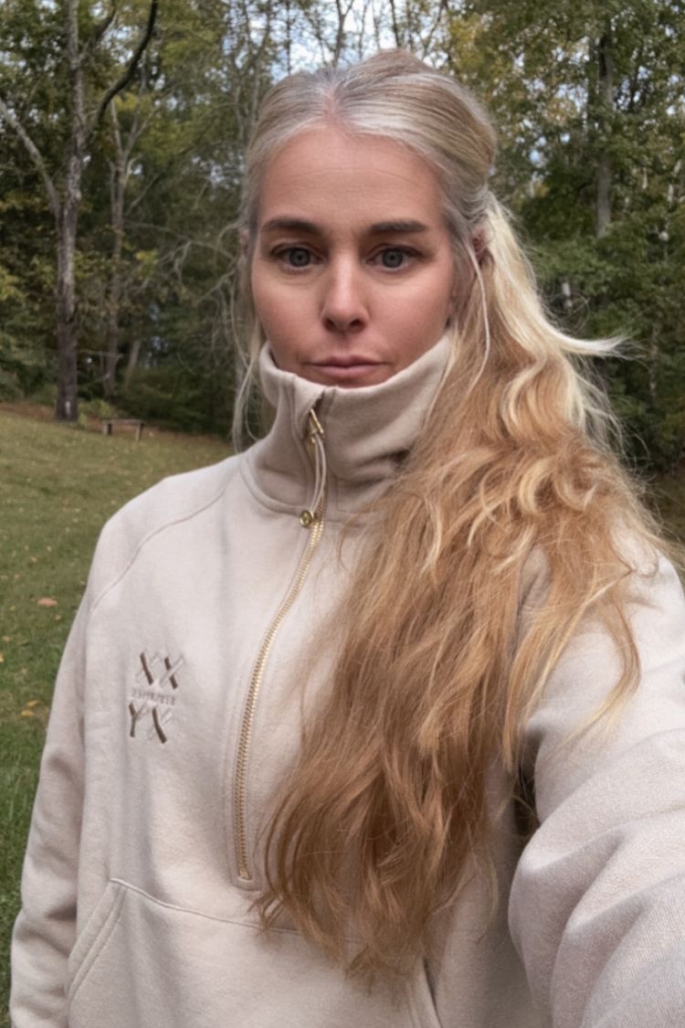 Person wearing a light-colored hoodie outdoors with trees in the background