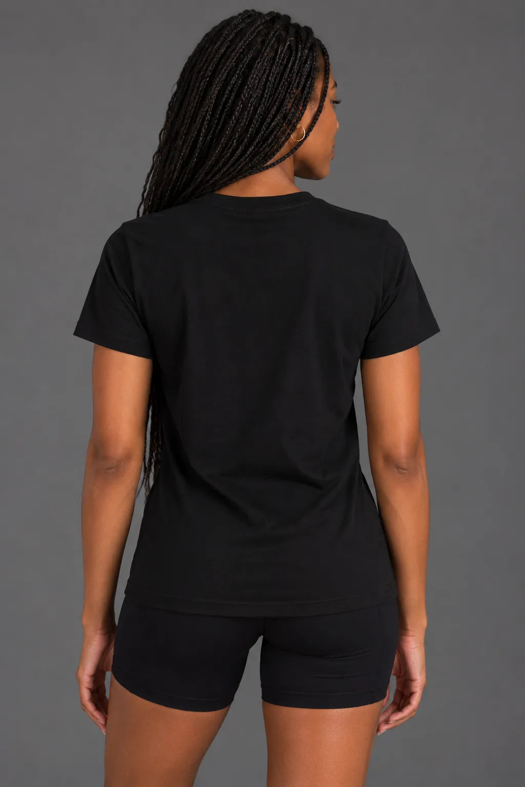 Back view of female model wearing a black XX-XY Athletics crewneck tee with a plain back and short sleeves