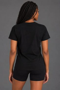 Back view of female model wearing a black XX-XY Athletics crewneck tee with a plain back and short sleeves || Black