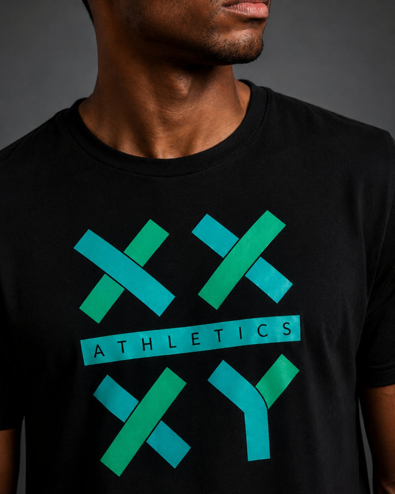 A close-up of a man wearing a black crewneck t-shirt with a teal and green athletic logo on the chest that reads 'ATHLETICS'.