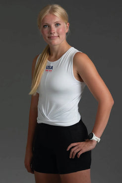 Woman wearing a white sleeveless top and black shorts on a gray background || White