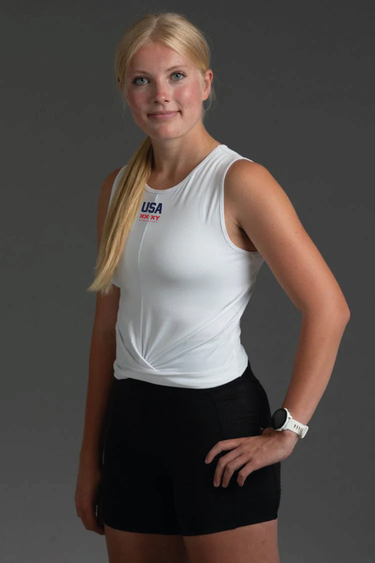 Woman wearing a white sleeveless top and black shorts on a gray background || White