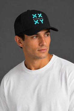 A man wearing a black baseball cap with a green and white embroidered logo that reads 'ATHLETICK' and 'XX', paired with a plain white t-shirt, set against a solid dark gray background. || Black with Color Logo