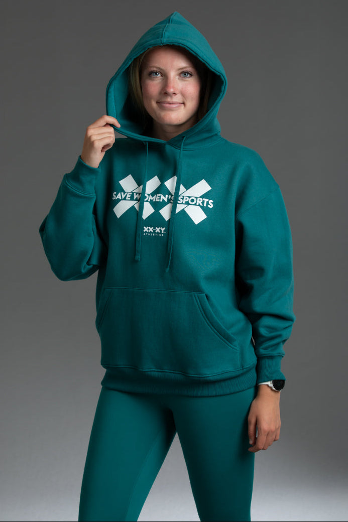 Person wearing a teal hoodie with a visible brand logo on a gray background || teal