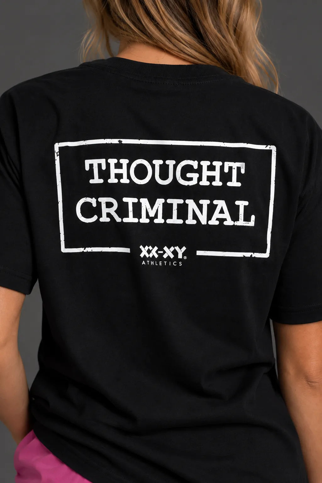 Close-up of the distressed white Thought Criminal and XX-XY Athletics graphic on the back of a black tee. || Black