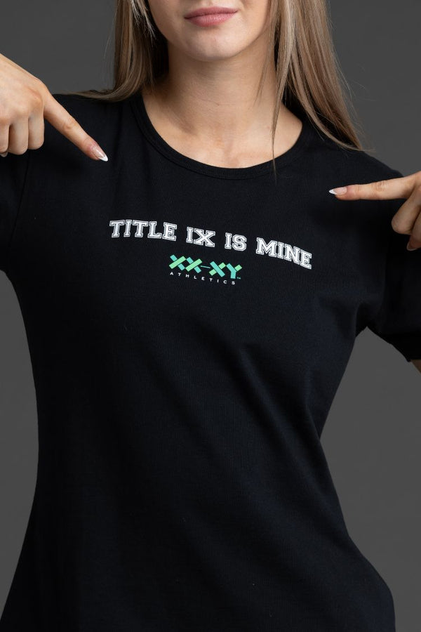 Person wearing a black t-shirt with 'TITLE IX IS MINE' text and pointing to it. || Black