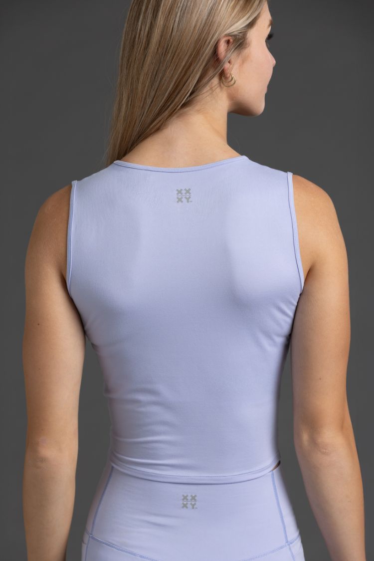 Person wearing a Lavender sleeveless top with a brand logo on a gray background || Lavender Gray