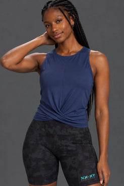 Black woman with braids wearing a navy twist-front tank and black camo bike shorts. || Indigo